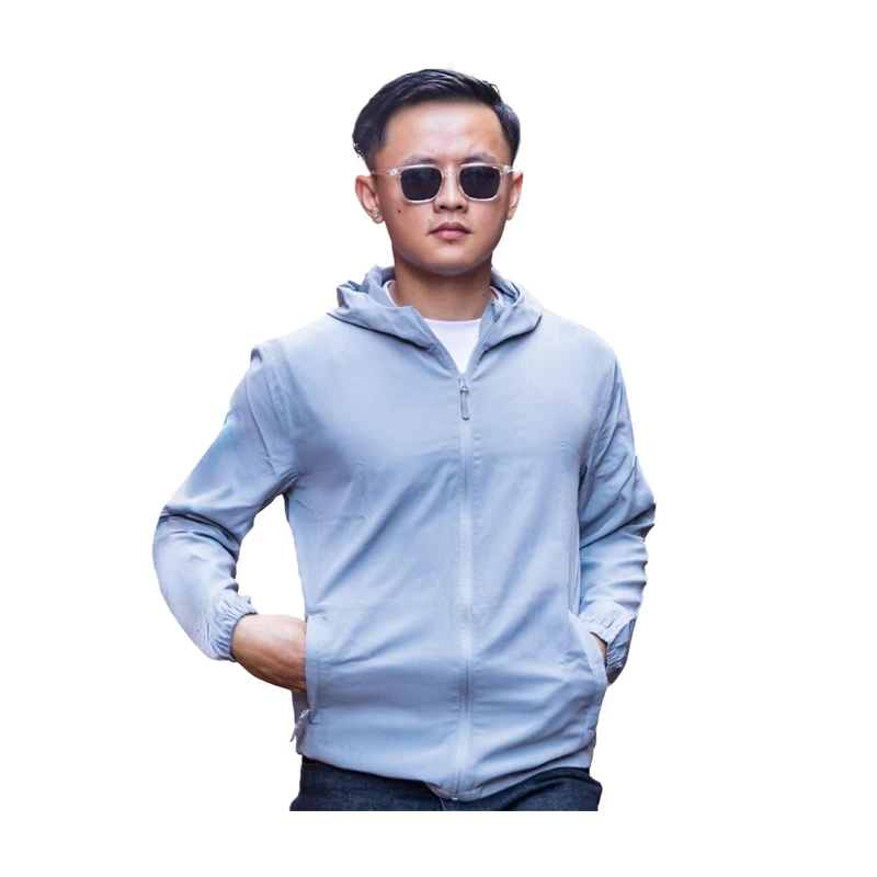 ront view of a man wearing a light blue hooded windcheater jacket over a white t-shirt, featuring a full front zipper and elastic cuffs with his hands resting in the side pockets