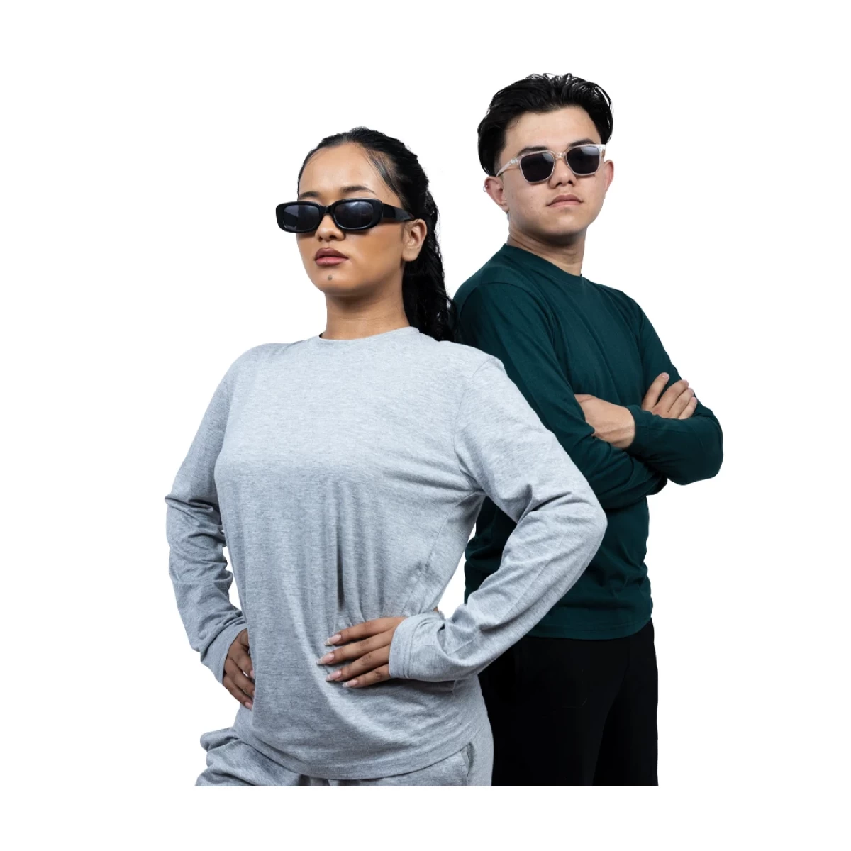 Two models showcasing casual loungewear tshirt. A woman in a light grey long-sleeve crewneck t-shirt and matching shorts stands next to a man wearing a dark green long-sleeve tshirt and black shorts
