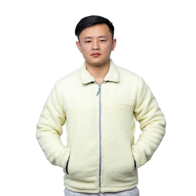 A model wearing a cream-colored sheep polyfiber unisex winter jacket featuring a classic fold-down collar, a full front zipper and hands resting in the side pockets