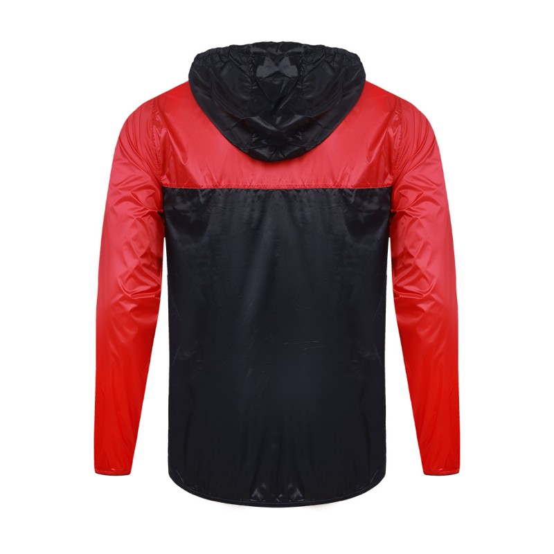 Front view of a male model styling a vibrant red and blue color-block lightweight windcheater jacket. This casual Unisex Windbreaker Jacket features a full zipper and a protective hood, making it a great outer layer for summer wear jacket. 5