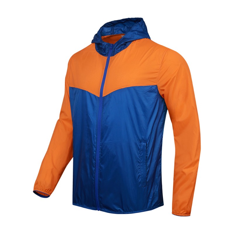 A smiling male model wearing the lightweight SkyShield Windcheater Jacket, featuring a bold red and bright blue color-block design, a full front zipper and an adjustable hood 0