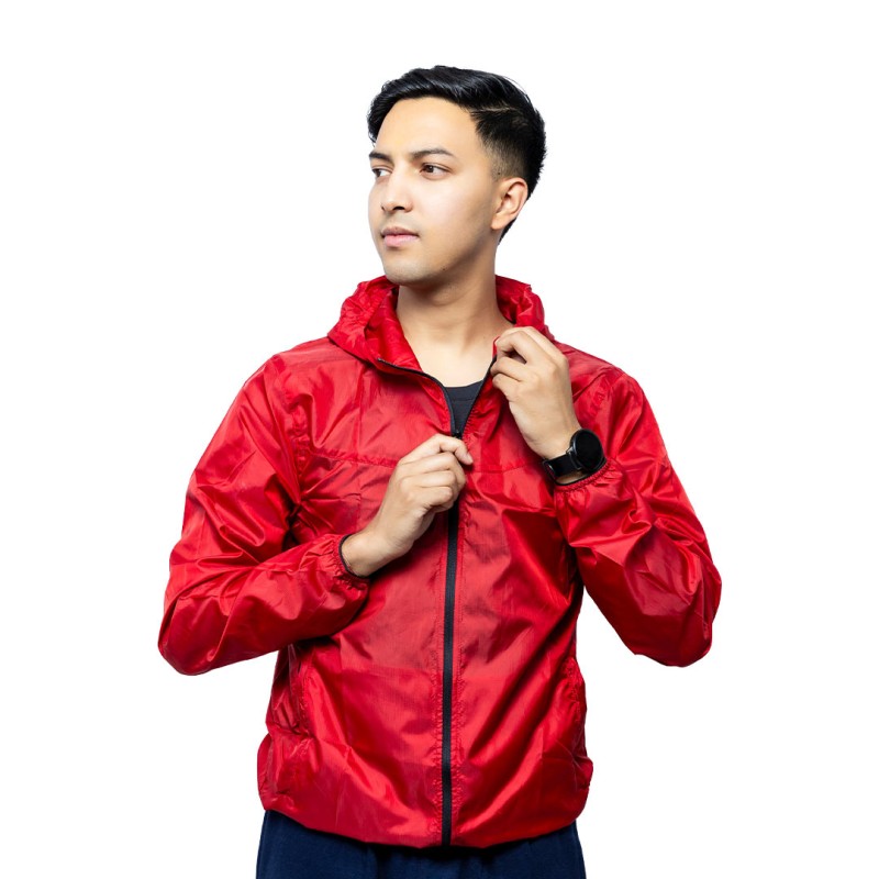 A male model adjusting the zipper of the lightweight, solid red Velocity Breeze Windcheater Jacket with hoodie, featuring a hood and a contrasting black front zipper